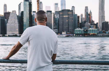 Young man standing with near metallic fence and river