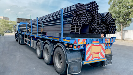 Trucks with long trailers carrying steel bars for building construction. Construction steel is...