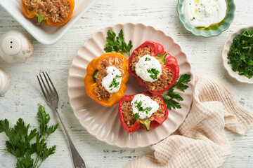 Roast stuffed red and yellow bell peppers with couscous, brown rice and spelled with Greek sauce and olive oil on rustic wooden background. Healthy dinner eating. Autumn cozy dinner concept. Top view