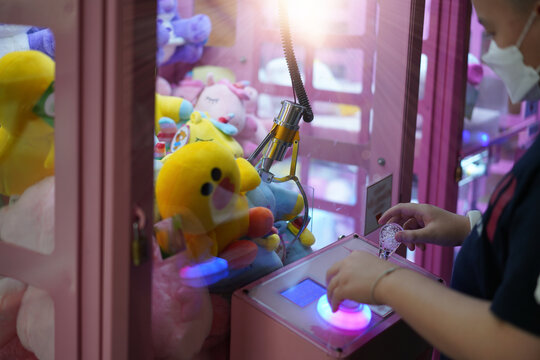 kid play claw game in game arcade ,pick up dolls by the hand claw.