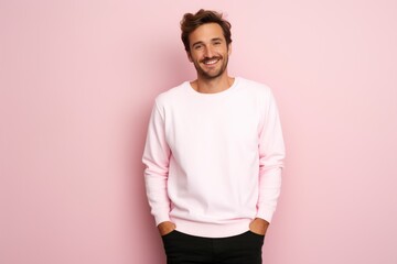 Portrait of a happy 30 - year - old man wearing a white t shirts with hands in pocket next to a light pink pastel background. Mock up t shirt concept.