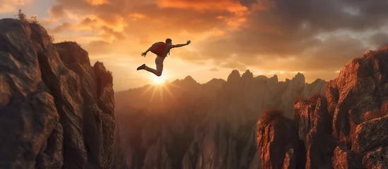 Foto op Canvas Businessman jumping over a cliff with a sunset in the background. © ismodin