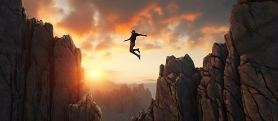 Businessman jumping over a cliff with a sunset in the background. - obrazy, fototapety, plakaty