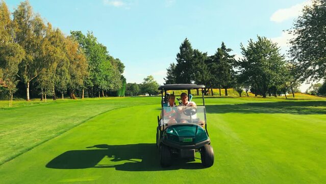 Drone shot of senior retired couple riding in golf buggy on course- shot in slow motion