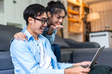 Young asian couple relaxing using laptop computer work and video conference meeting online chat.Creative business couple planning strategy analysis and brainstorm at home