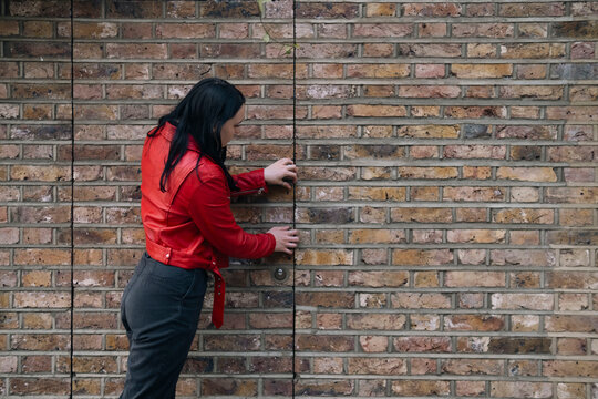 Young woman opening door near brick wall