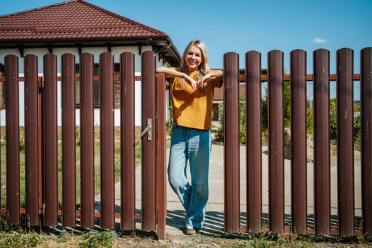 Smiling blond woman standing near fence