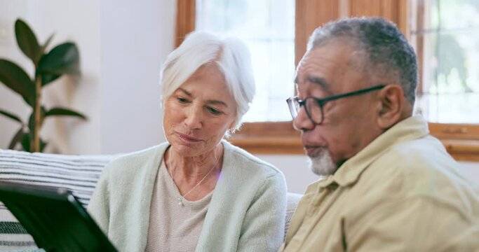 Senior couple, tablet and talking in home while reading news app, social media and ebook on sofa. Old man, woman and interracial partner scroll on digital blog, online shopping or relax in retirement