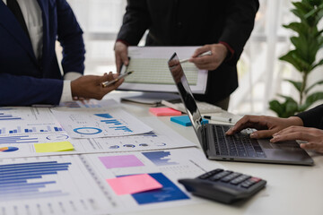 Close-up of a business team sitting at a desk in front of a laptop with a financial infographic and financial document of a startup company brainstorming a new project in a coffee shop.