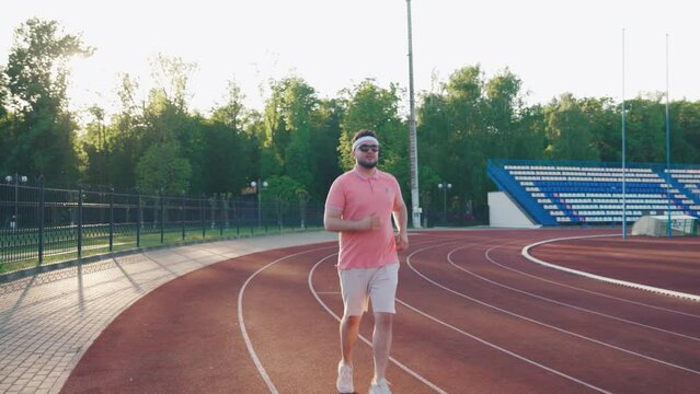An overweight man in sportswear on a morning jog. Running body workout. Cardio training and health.