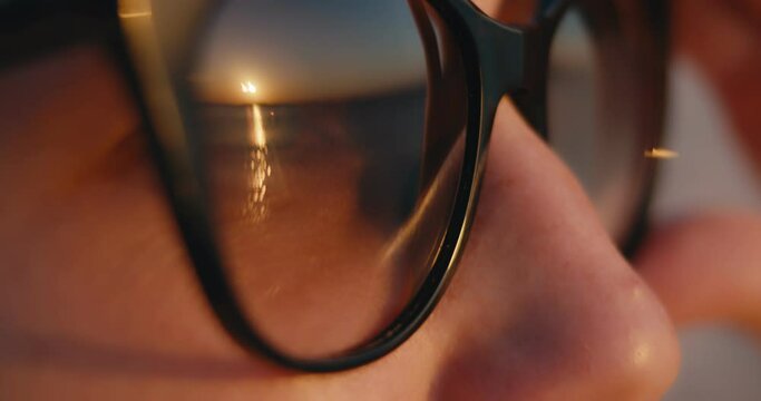 Sunset sun reflection sunglasses seaside sea woman in macro close up