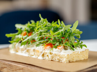 Tasty bruschetta with salmon and arugula on restaurant table in interior