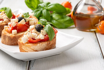 Bruschette alla caprese con olio di oliva, mozzarella, pomodoro fresco, origano e basilico, spuntino italiano, dieta mediterranea  