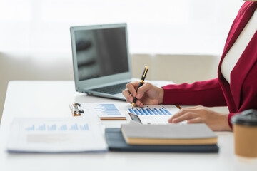 A young Asian real estate agent is reviewing documents and calculating interest rates to inform tenants of monthly installments before entering into contracts to buy or sell real estate.