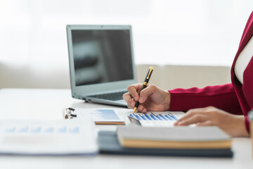 Fototapeta premium A young Asian real estate agent is reviewing documents and calculating interest rates to inform tenants of monthly installments before entering into contracts to buy or sell real estate.