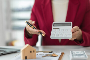 A young Asian real estate agent is reviewing documents and calculating interest rates to inform...