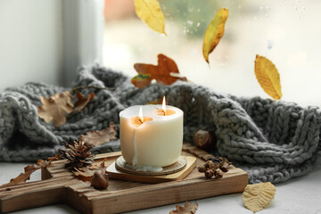 Autumn still life with a burning candle, leaves and a knitted element.