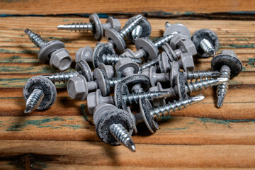 Group of roofing screws on a wooden texture background - obrazy, fototapety, plakaty