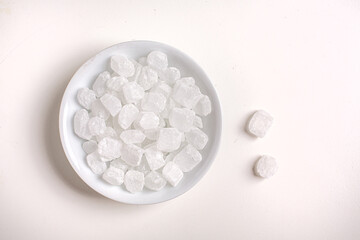 sugar crystals inside a white bowl on a white background top view