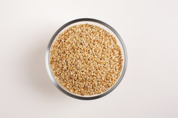 sesame seeds in glass bowl on white background shot from above