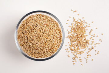 sesame seeds in glass bowl on white background shot from above