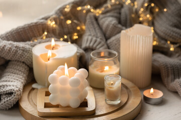 A cozy composition with candles, a knitted element and a garland.