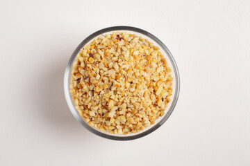 chopped hazelnuts in glass bowl on white background shot from above