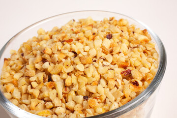 chopped hazelnuts in glass bowl on white background top view