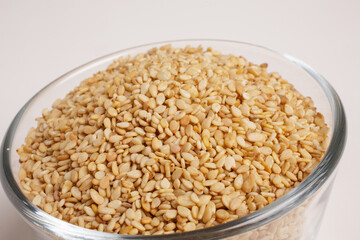 sesame seeds in glass bowl on white background top view