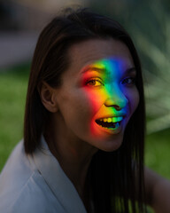 Portrait of caucasian woman with rainbow beam on her face outdoors.