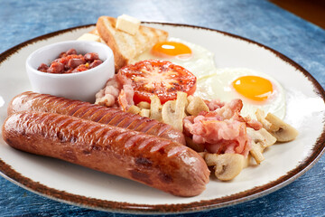 Breakfast with fried eggs, bacon, sausages, beans, tomatoes