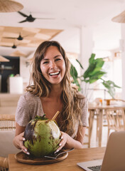 happy female copywriter smiling at camera in Indonesian wicker cafe