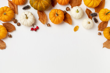 Autumn seasonal background from decorative pumpkins, dried foliage, pinecones and acorns top view....