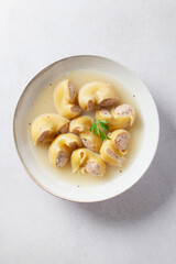 Traditional Catalan Christmas dish Escudella in white plate on table, stuffed pasta in meat broth, top view
