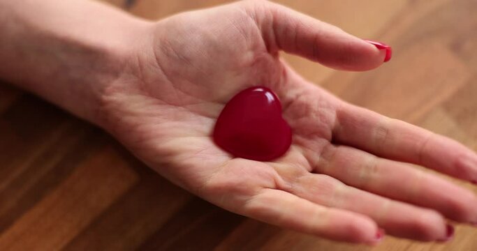 Woman hand with red manicure opening into palm with heart closeup 4k movie. Romantic relationship concept