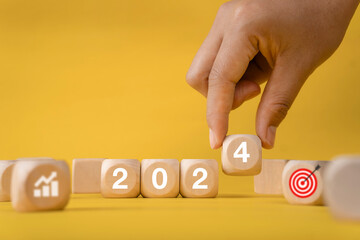 Business growth goals and success goals, hand holding wooden blocks with numbers, year 2024, graph...
