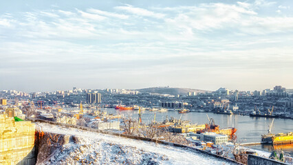 Fototapeta na wymiar Panoramic view of the city and the bay in cold warm colors, winter landscape of the Golden Horn Bay Vladivostok 11.22.2020, Water and ships reflect the sunset. 