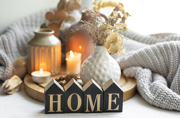 A cozy composition with the wooden word Home, candles and a knitted element.