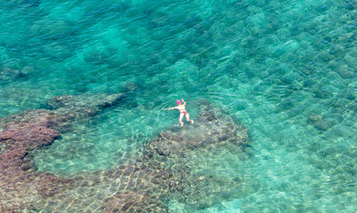 Woman swim in open sea in turquoise water. View from above