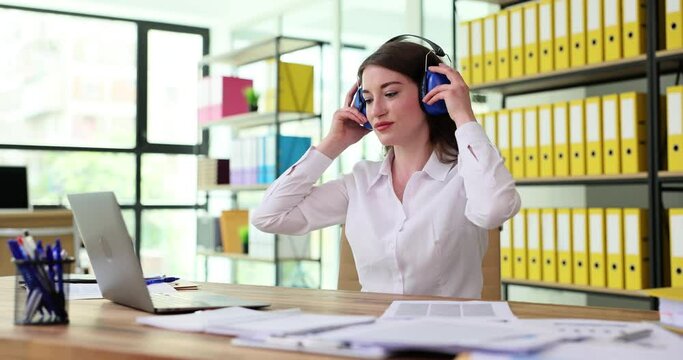 Businesswoman working at computer wearing antinoise headphones in office 4k movie slow motion. How it works in noisy rooms during renovation concept 