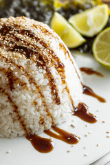 Close-up, rice topped with sauce and sprinkled with sesame seeds.