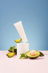Beauty product packaging design templates based on avocado. White plastic bottle displayed on podium with fresh avocado slices on blue background. Front view