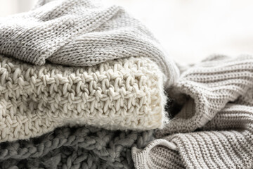Close up of folded knitted items of grey color on a light background.