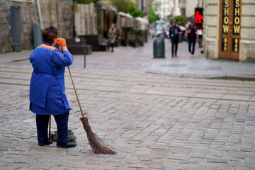 UKRAINE. Lviv. July 2023: City janitor. A woman who cleans, sweeps the streets of the city, stands...