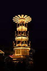 Christmas wooden pyramid rotates with nativity scene, people walking during Christmas market,...