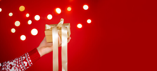 Girl hands holding christmas gift on red background. Christmas banner. Minimalism. Copyspace.