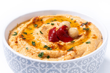 Roasted red pepper hummus in white bowl isolated on white background