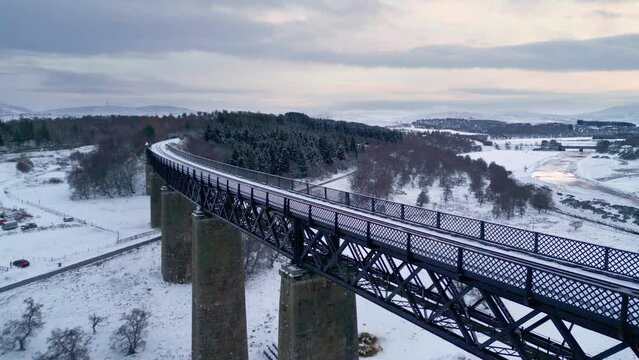 Flying above Findhorn Viaduct as a flock of sheep gather in the snow covered field