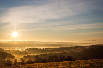 Fall landscape from above. Cold morning weather. Autumn mist with sunbeams over countryside during...