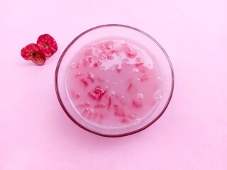 smoothie in glass. Candil porridge, a traditional snack made from starch and then eaten with coconut milk. chewy, sweet and savory. pink snacks. Bubur candil on pink background. Top view